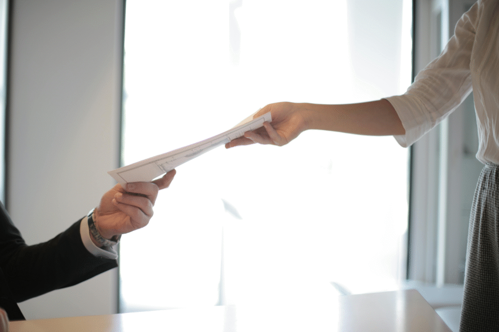 person handing over a printed resume during a job application or interview process in a professional setting