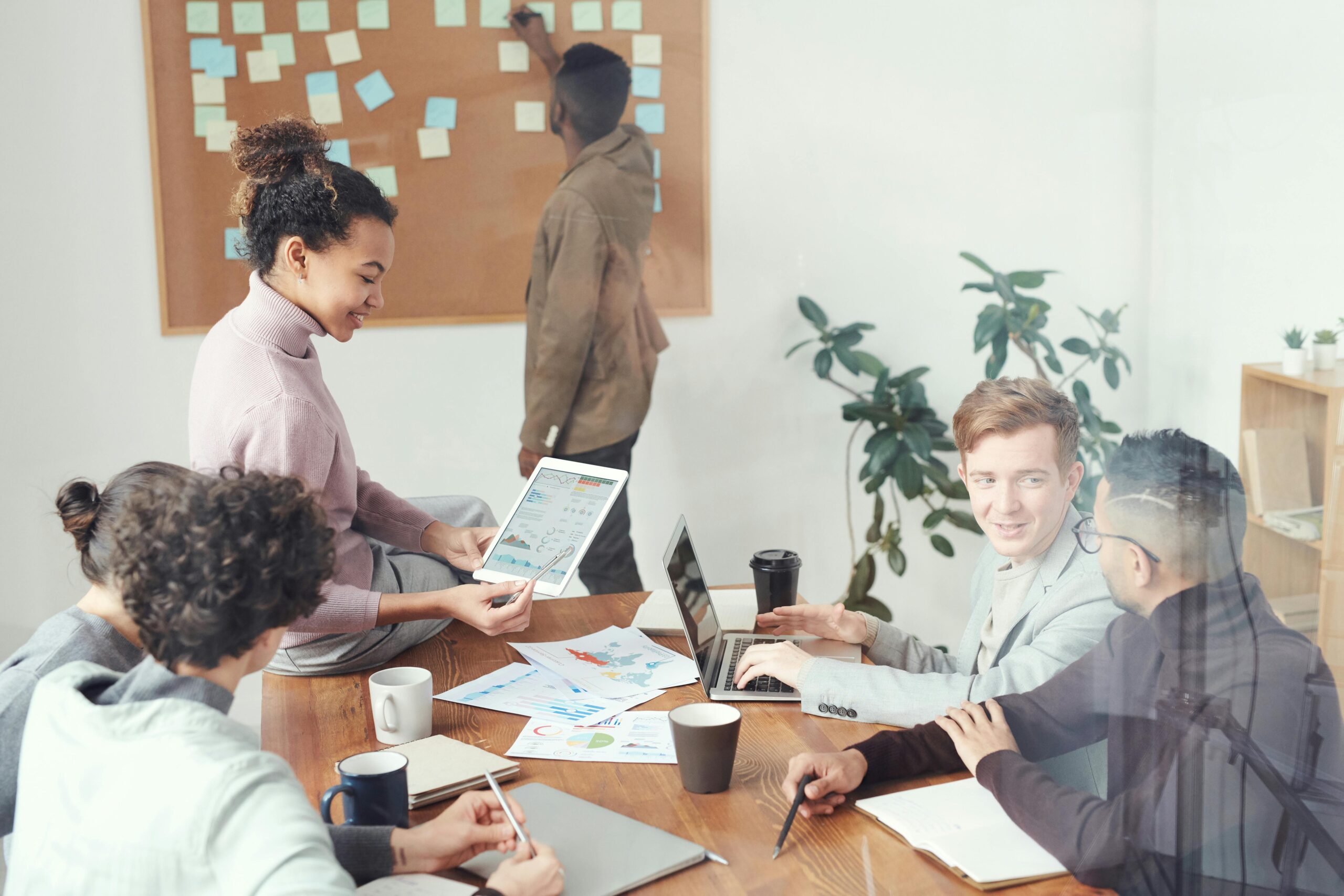 people in a meeting room discussing data and strategy around a table with laptops and charts, collaborating to build a meaningful career